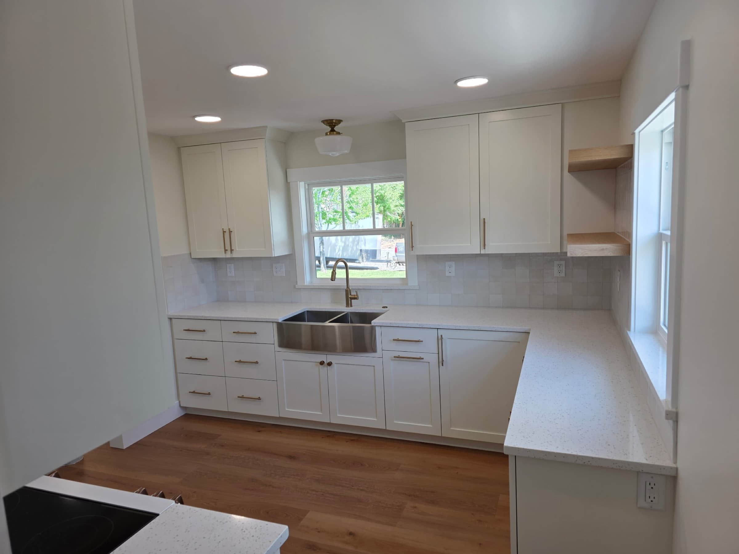 White shaker kitchen with a stainless farmhouse sink and quartz counters