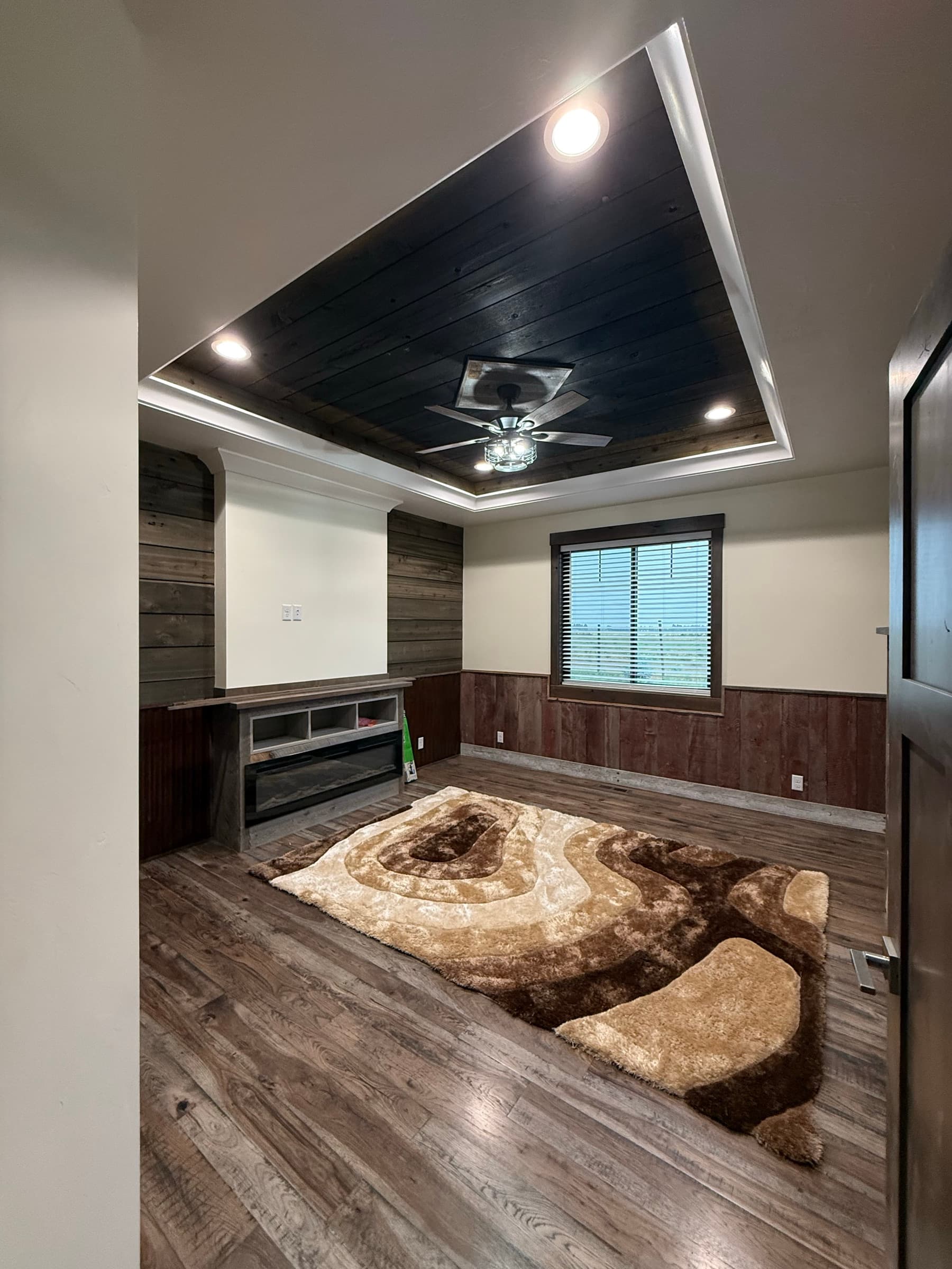 Living room with a wood-clad tray ceiling and rustic wainscot