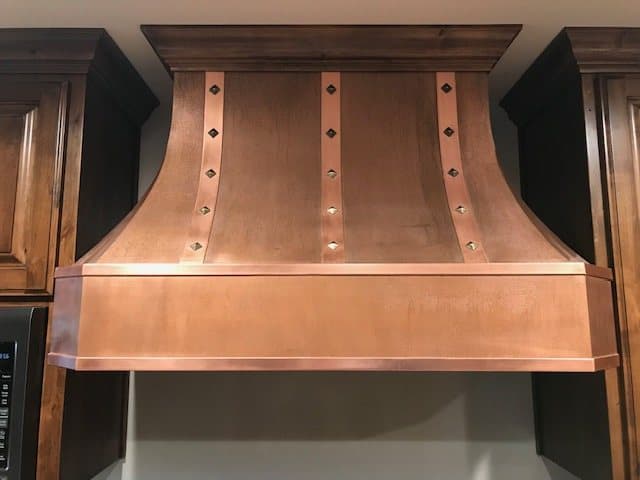 Hand-hammered copper range hood over a gas range