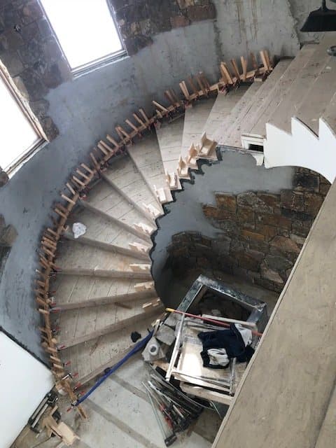 Grand curved staircase with wood treads and an iron railing