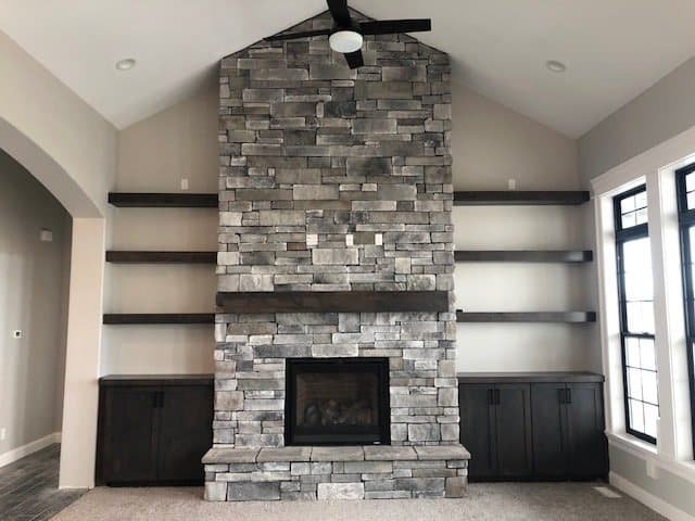 Floor-to-ceiling stone fireplace with built-in shelving